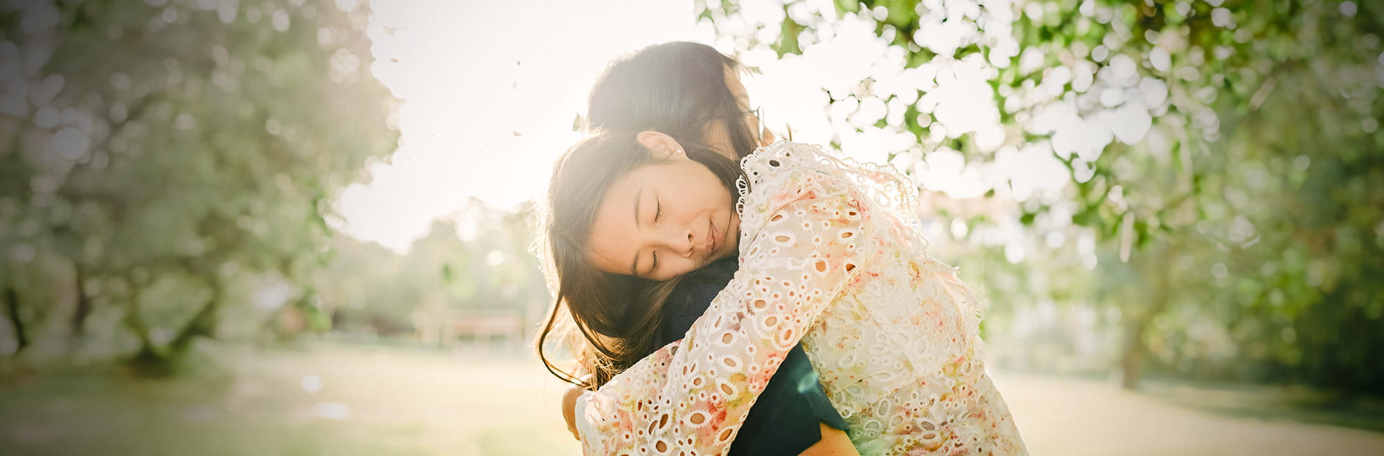 People hugging in a sunny field.