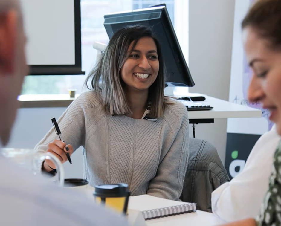 Aurecon employee smiling in meeting while taking notes.